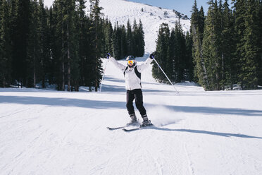 Eine Skifahrerin, eine junge Frau auf Skiern mit ausgestreckten Armen, auf der Piste. - MINF03328