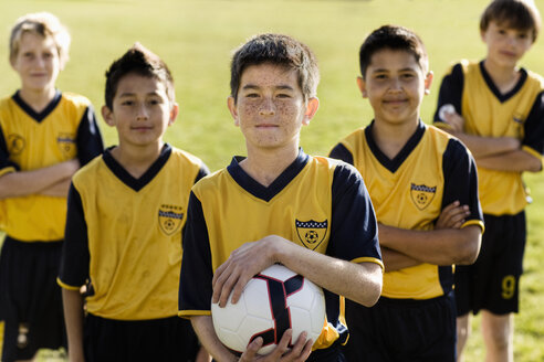 Eine Gruppe von Jungen in Fußballtrikots, einer hält einen Fußball. - MINF03391