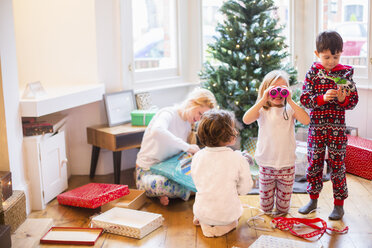 Eine Mutter und drei Kinder öffnen am Weihnachtsmorgen ihre Geschenke. - MINF03401