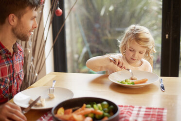 Ein Kind und ein Mann sitzen an einem Tisch und essen eine gekochte Mahlzeit. - MINF03412