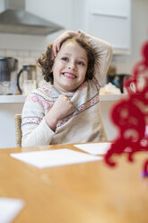 Ein Kind, ein Mädchen, das zu Hause an einem Tisch sitzt und vor Weihnachten Karten malt und schreibt. - MINF03418