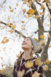 A teenage girl outdoors throwing autumn leaves into the air. - MINF03433