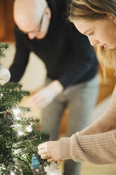 A father and daughter decorating a Christmas tree. - MINF03437