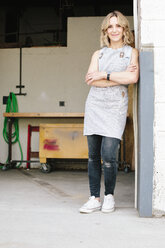 Eine Unternehmerin und Handwerkerin, die in der Tür ihrer Werkstatt steht. - MINF03440