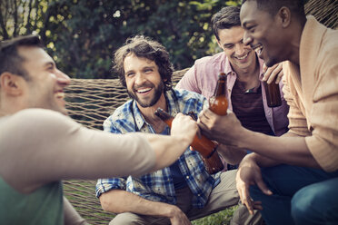 Eine Gruppe von Freunden, die in einer großen Hängematte im Garten liegen, ein Bier trinken und ein Selfie machen. - MINF03460