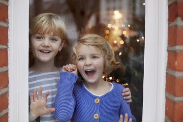 Two children, a boy and girl, looking out of a window at home with excited expressions. - MINF03486