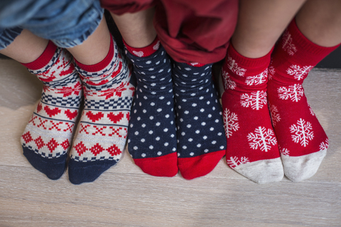 Drei Paar Kinderfüße in bunt gemusterten Weihnachtssocken., lizenzfreies Stockfoto