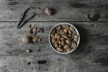 A bowl of mixed nuts, shells and a nutcracker on a table. - MINF03517