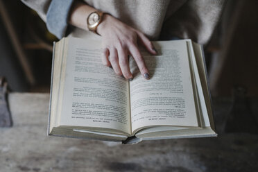 Eine Frau liest in einer Küche aus einem Rezeptbuch. - MINF03518