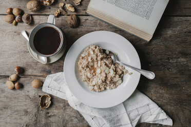 Ein Tisch mit einer Tasse Kaffee, einer Schale Müsli, Nüssen und einem offenen Buch. - MINF03519