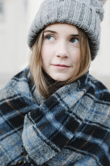 Ein junges Mädchen mit Schottenkaro-Schal und Wollmütze im Freien im Winter. - MINF03541