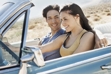 Ein junges Paar, Mann und Frau, in einem hellblauen Cabrio auf offener Straße - MINF03587