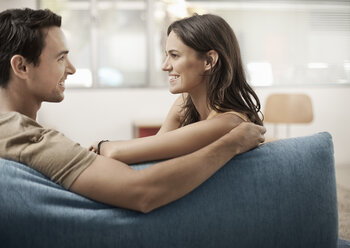 Ein junges Paar, das auf einem Sofa sitzt und sich anschaut, ein Mann und eine Frau, Freund und Freundin. - MINF03603
