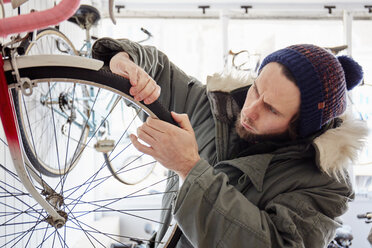 A young man working in a cycle shop, repairing a bicycle. - MINF03612