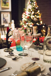 Ein für ein Weihnachtsessen gedeckter Tisch, mit Silber- und Kristallgläsern und einem Weihnachtsbaum im Hintergrund. - MINF03613