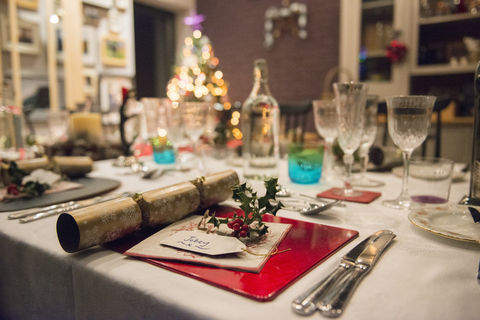 Ein für ein Weihnachtsessen gedeckter Tisch, mit Silber- und Kristallgläsern und einem Weihnachtsbaum im Hintergrund., lizenzfreies Stockfoto