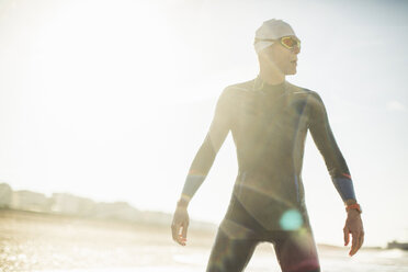 A swimmer in a wet suit, swimming hat and goggles on a beach. - MINF03631