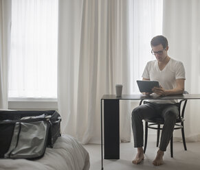 Ein Arbeitstag: Ein Mann sitzt an einem Laptop und arbeitet in einem Hotelzimmer. - MINF03635