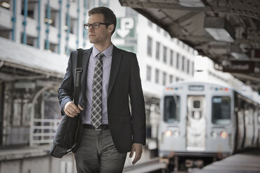 Ein Arbeitstag: Geschäftsmann im Arbeitsanzug und mit Krawatte auf einem Bahnsteig. - MINF03640