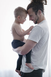 Ein junger Mann hält ein kleines Kind im Arm. - MINF03703