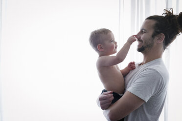 A young man holding a small child in his arms. - MINF03704