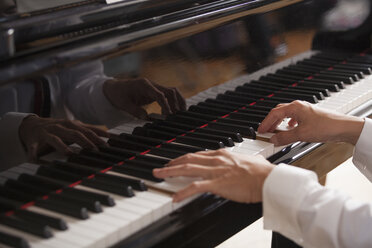 Nahaufnahme der Hände eines Pianisten, der auf einem Flügel spielt. - MINF03726