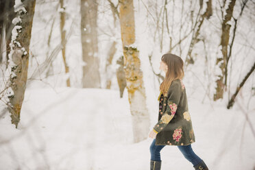 Eine Frau geht im Schnee im Wald spazieren. - MINF03727