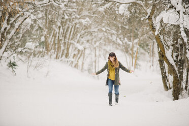 Eine Frau geht im Schnee im Wald spazieren. - MINF03728