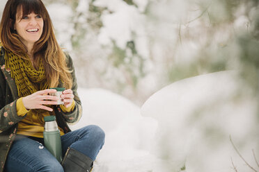 Eine Frau im Schnee im Winter, die eine warme Tasse Kaffee trinkt. - MINF03729