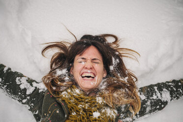 Eine Frau liegt mit ausgestreckten Armen auf einer Schneewehe. - MINF03732