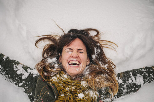 A woman lying on a snow bank with her arms stretched out. - MINF03732