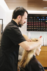 Ein Friseur kämmt das Haar eines Kunden aus. - MINF03740