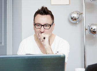 Man sitting at a desk in an office using a laptop. - MINF03772