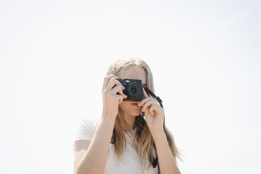 Teenager-Mädchen mit langen blonden Haaren schaut durch eine Kamera und macht ein Foto. - MINF03799