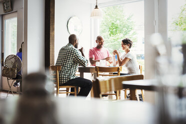 Two men and a woman sitting at a table in a cafe, having lunch. - MINF03838