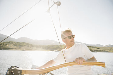 Porträt eines blonden Mannes mit Sonnenbrille, der ein Segelboot steuert. - MINF03870