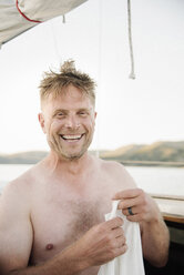 Smiling shirtless man standing on sail boat. - MINF03894