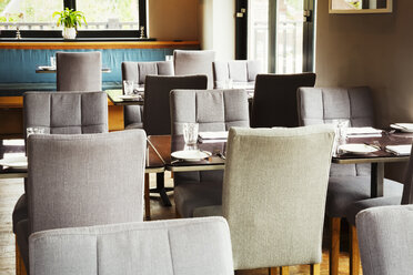 View of tables and grey upholstered chairs in a restaurant. - MINF03900