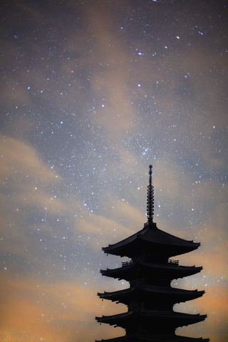 Silhouette einer hohen Holzpagode eines buddhistischen Tempels gegen den Abendhimmel., lizenzfreies Stockfoto