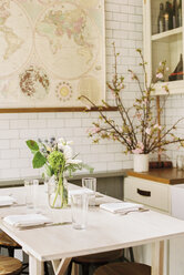 A small table with four place settings and flowers in a jar. - MINF03982