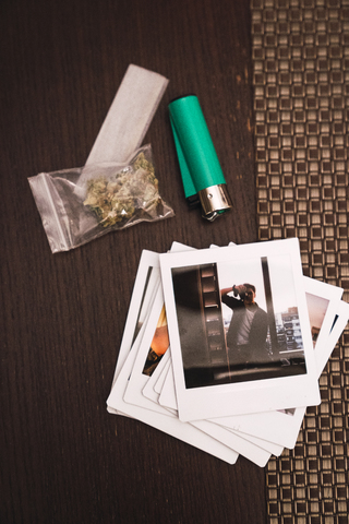 Marihuana, Zigarettenanzünder und Polaroids auf Holz, lizenzfreies Stockfoto