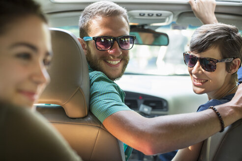 Eine Gruppe von Menschen in einem Auto, auf einer Autoreise, Blick vom Rücksitz. - MINF04075