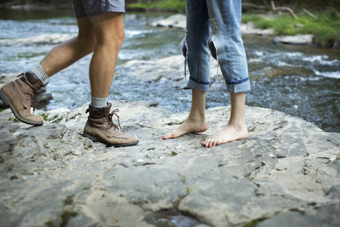 Zwei Personen auf den Felsen an einem reißenden Fluss, Mann und Frau, Unterschenkel und Füße. - MINF04093