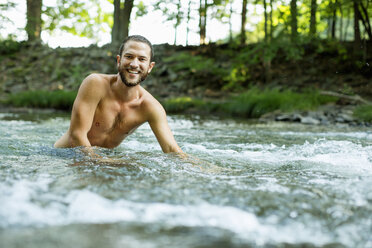 Ein junger Mann schwimmt in einem schnell fließenden, kühlenden Bach. - MINF04098