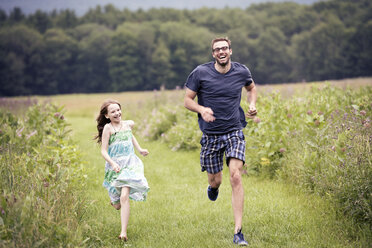 Ein Mann und ein kleines Kind laufen durch eine Wildblumenwiese. - MINF04109