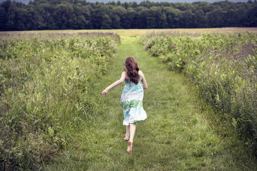 Ein Mädchen läuft im Sommer über eine Wiese. - MINF04113