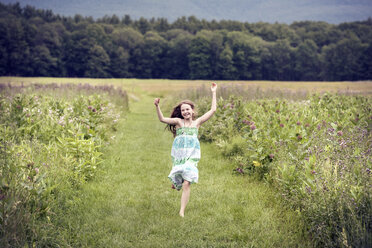 A girl running through a meadow with her arms above her head. - MINF04114