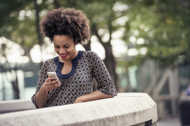 A woman in a park checking her cell phone - MINF04132