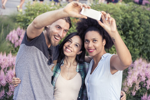Zwei Frauen und ein Mann posieren für ein Selfie - MINF04140