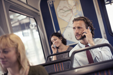 Drei Personen in einem Bus, zwei telefonieren mit ihren Handys - MINF04148